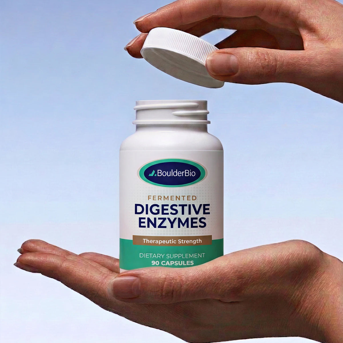 BoulderBio Digestive Enzymes bottle held in one hand with its lid lifted.